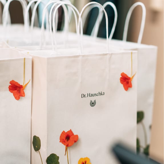 Paper shopping bag with Dr. Hauschka Natural Skincare logo and orange flowers