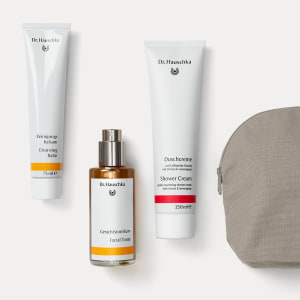 Duschcreme 150 ml, Gesichtstonikum Spray und Reinigungsbalsam 75 ml von Dr. Hauschka Naturkosmetik neben grauem Kulturbeutel