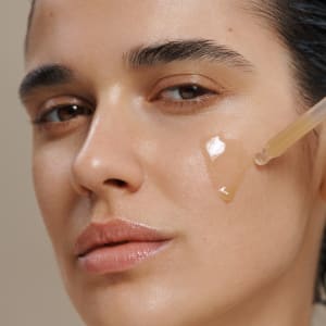 Nahaufnahme eines Gesichts mit Serumtropfen aus Pipette