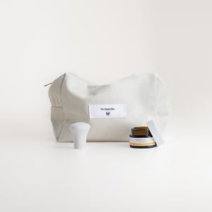 Augenbalsam von Dr. Hauschka Naturkosmetik neben beiger Kulturtasche