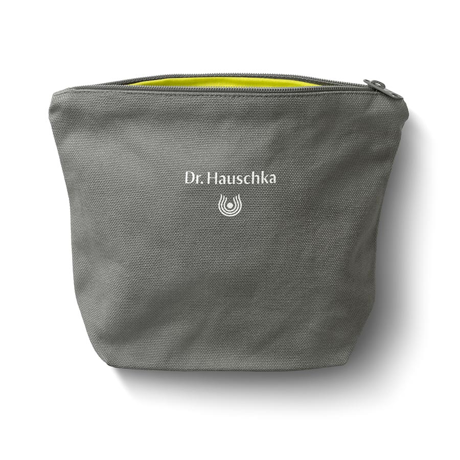 Graue Kosmetiktasche mit Text Dr. Hauschka Naturkosmetik und gelbem Innenfutter