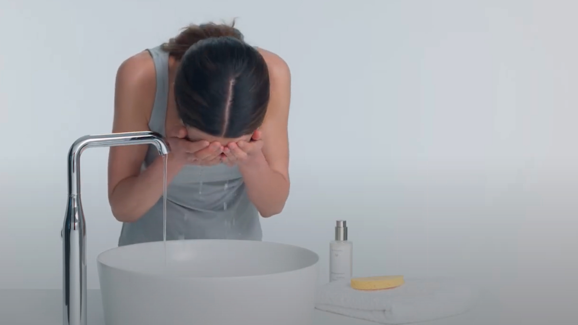 Atmospheric image of a person washing face with Dr. Hauschka Natural Skincare bottle visible