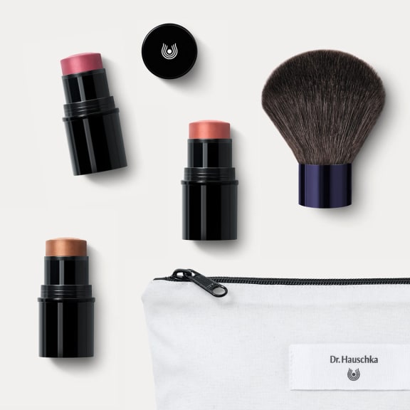 Dr. Hauschka Naturkosmetik Makeup-Sticks in schwarzen Hüllen, Kabuki-Pinsel und weiße Tasche