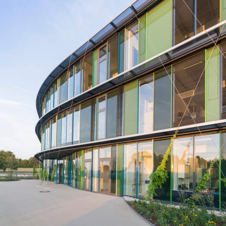 Dr. Hauschka Naturkosmetikin yritysrakennus, kaareva lasijulkisivu vihreillä paneeleilla