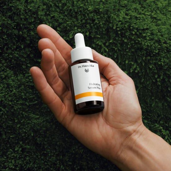 Hydrating Serum Plus von Dr. Hauschka Naturkosmetik in brauner Tropfflasche, in Hand