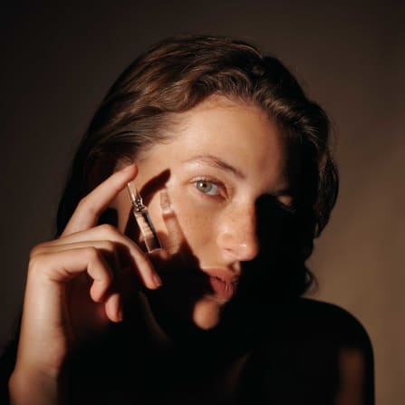 Ampoule serum from Dr. Hauschka Natural Skincare held near the face